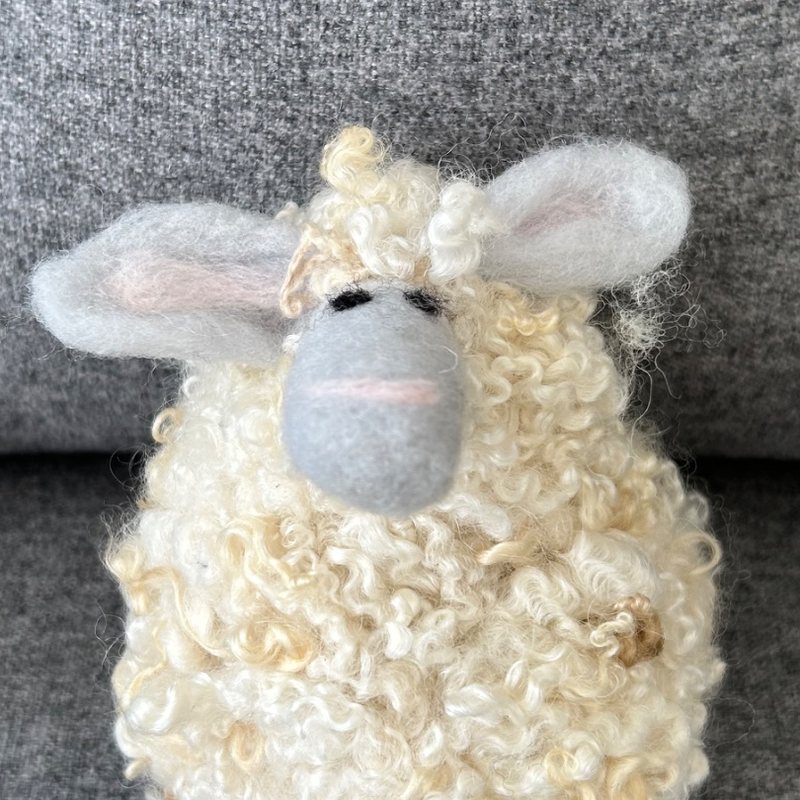 A needle-felted sheep made of curly locks